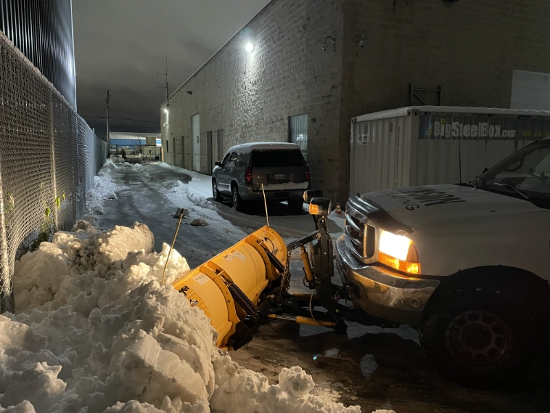 atkinson truck with a snow plow plowing a parking lot