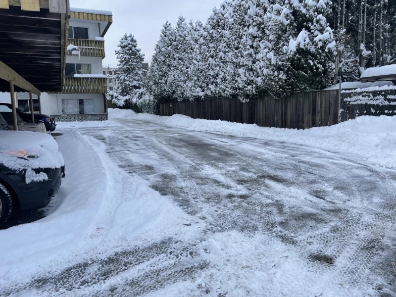 a freshly plowed strata parking lot with cars parked in the snow