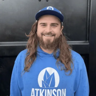 atkinson landscaping staff travis wearing a blue atkinson hoodie against a black background